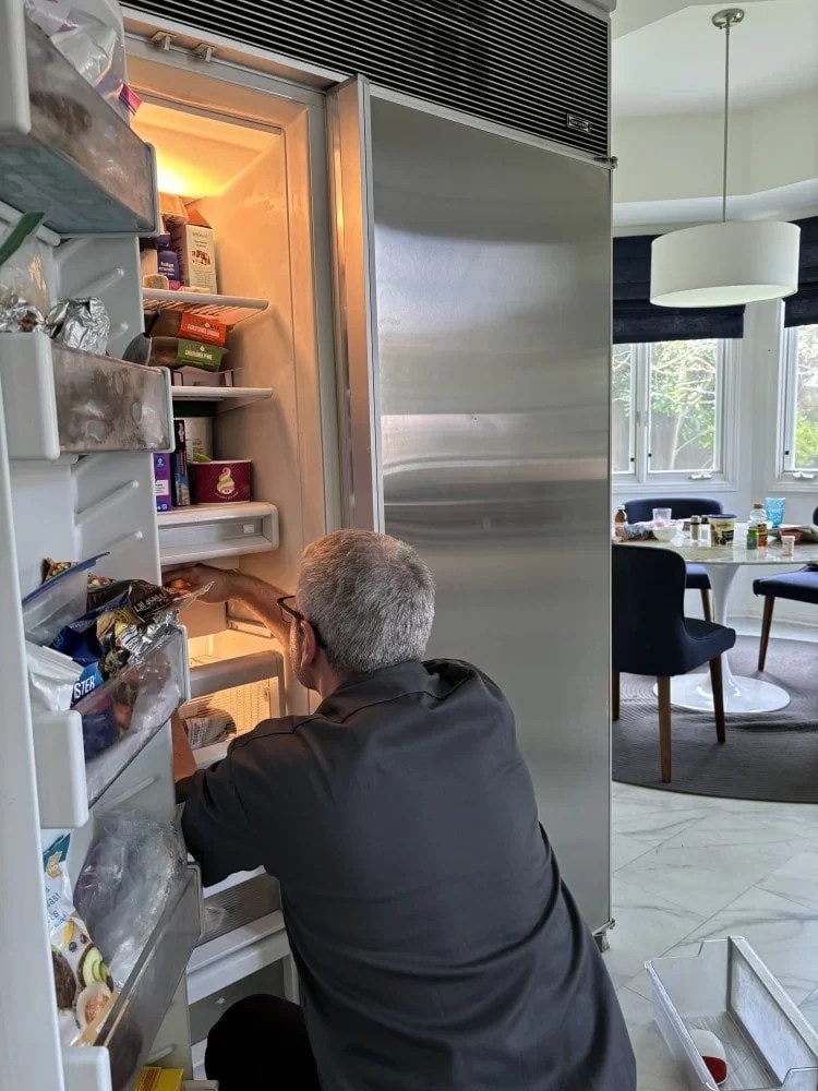 Technician servicing a built-in refrigerator